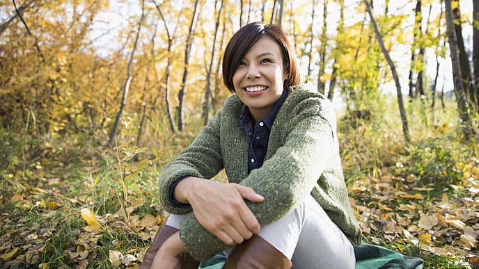 smiling woman sitting in the woods