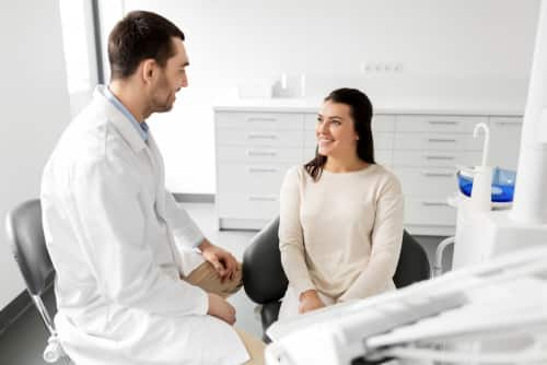 Dentist and patient smiling at each other in office