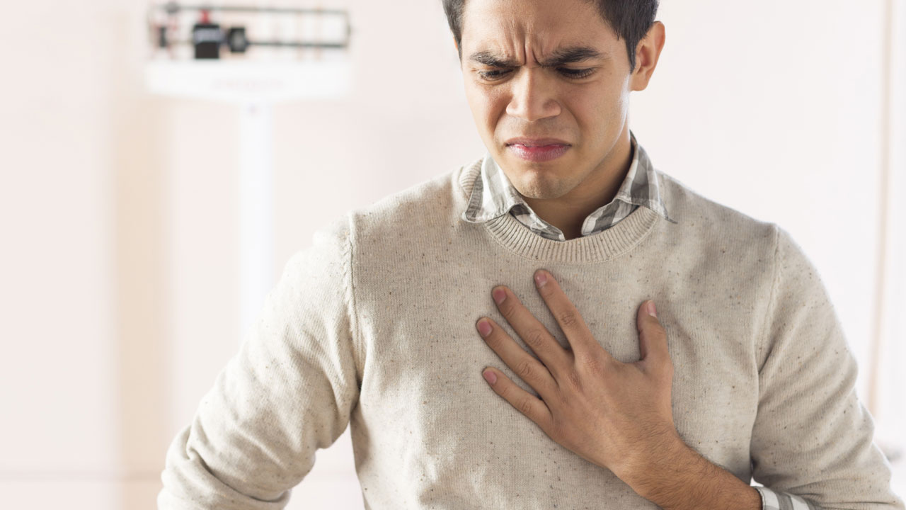 man frowning while holding his chest