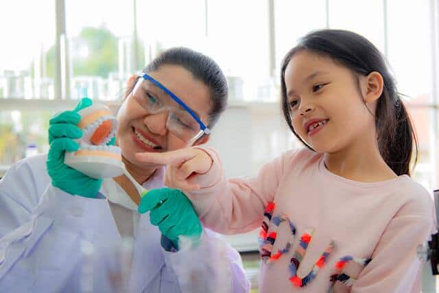 Diş hekimi genç bir kıza dişlerini nasıl fırçalayacağını öğretiyor