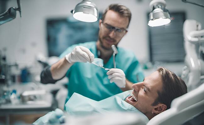Korkan bir hastaya tedavi uygulayan dişçi
