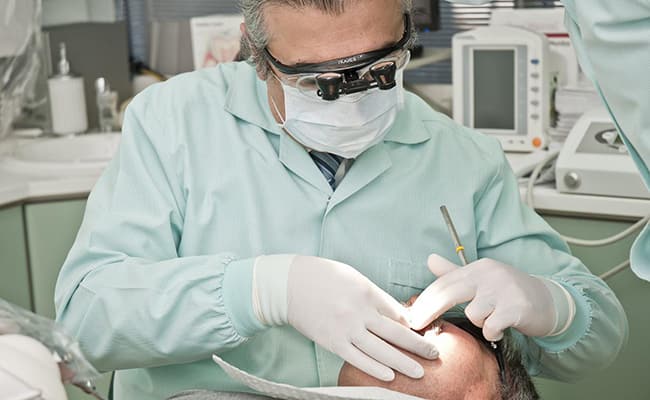 Diş hekimi hastasına beyazlatma tedavisi uyguluyor